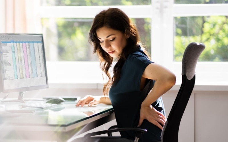 Woman experiencing back pain at the computer