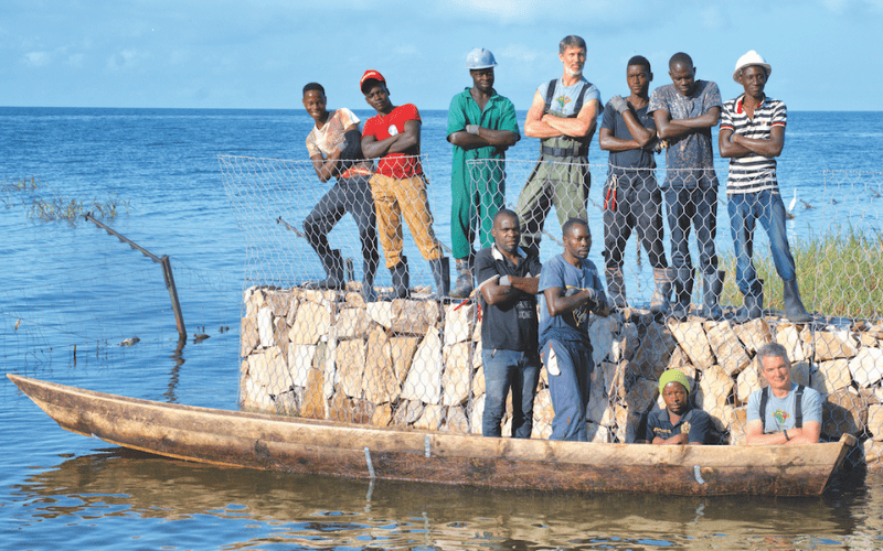 Men standing on wall and in boat